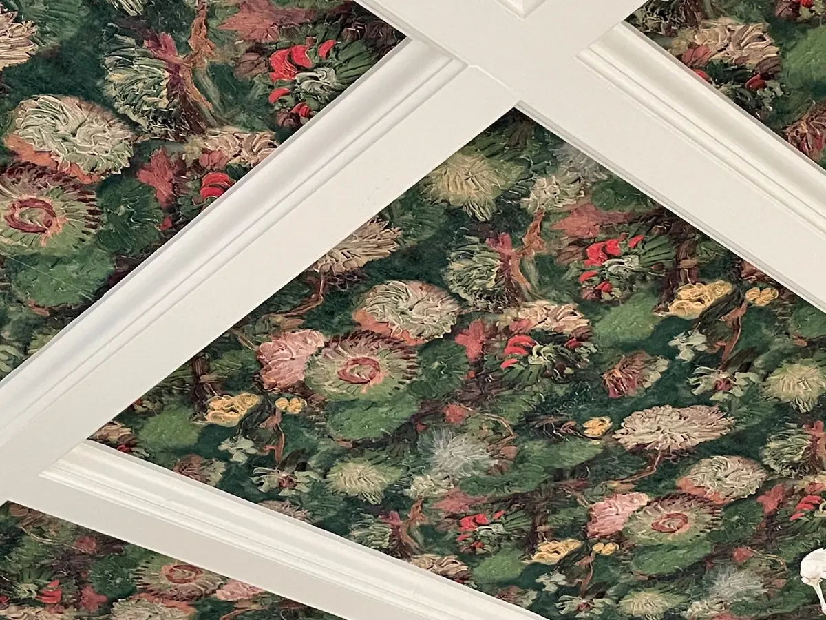 Coffered ceiling with dark floral wallpaper between white beams