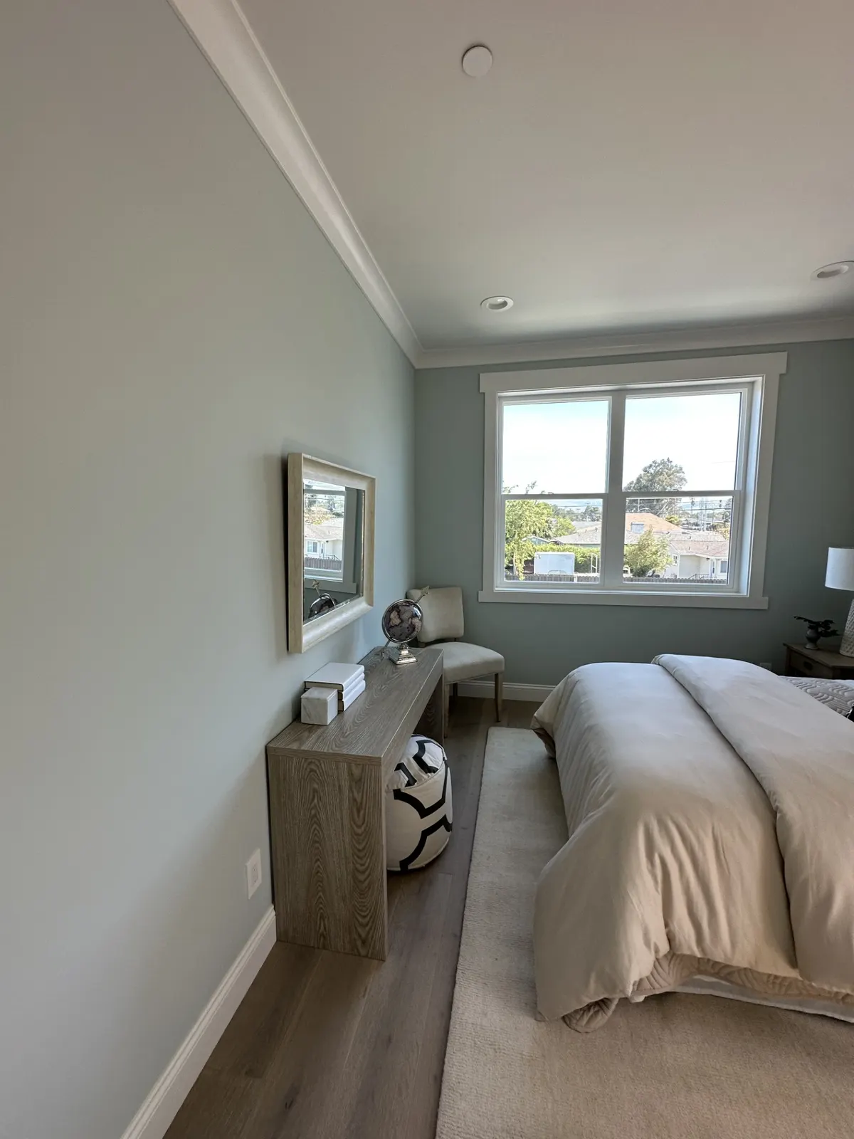 Bright bedroom with soft gray-green walls, white trim, and a large window