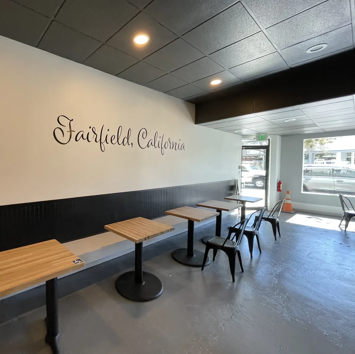 Cafe dining room with white walls, a black ceiling, and wood tables