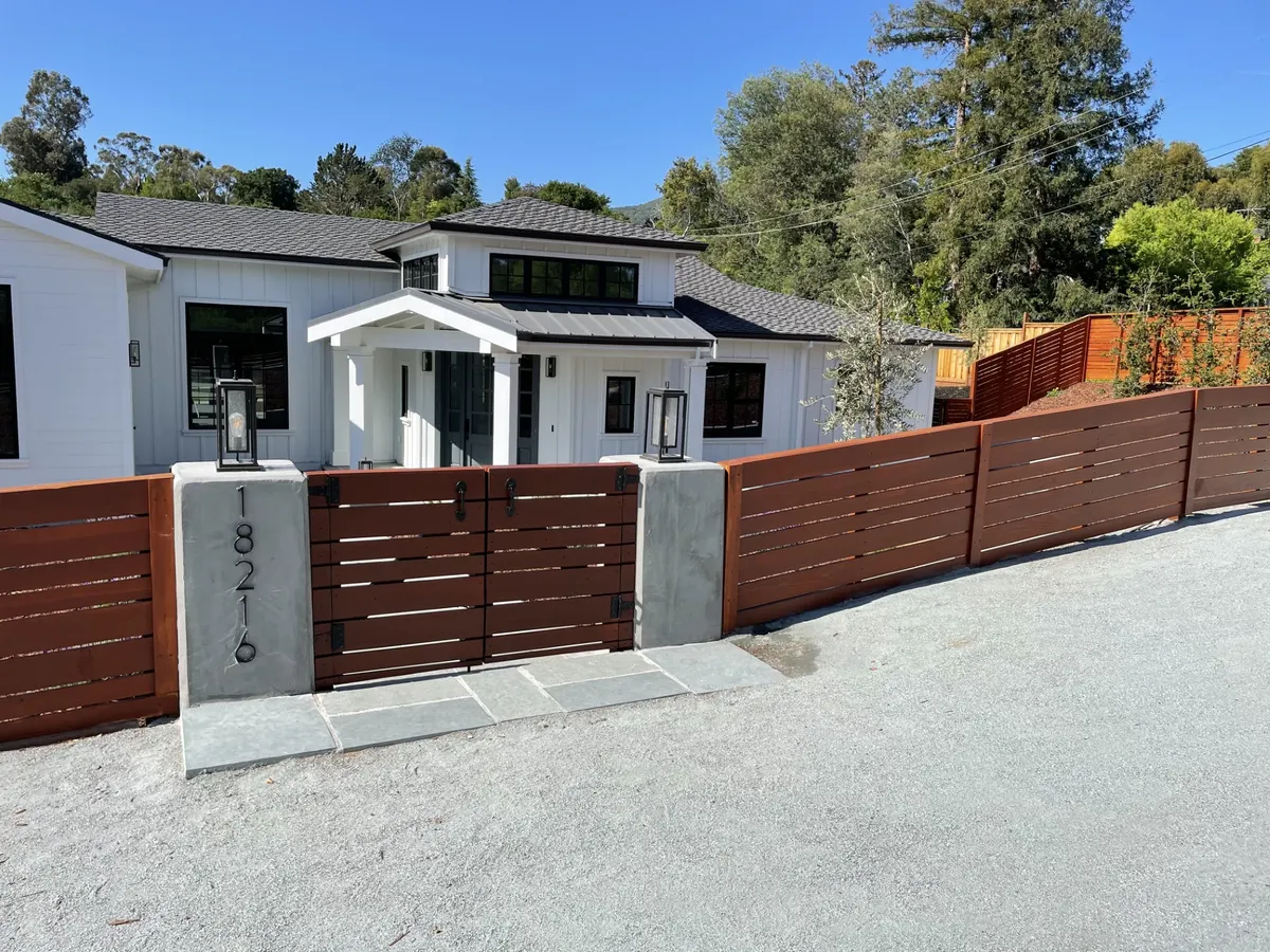 Long horizontal wood fence stained a warm red-brown along a street