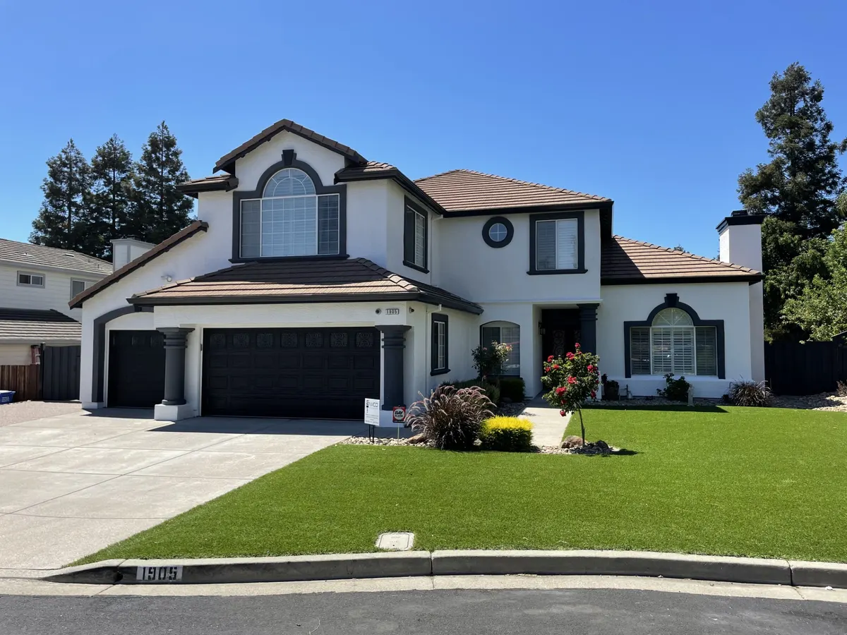 Two-story home painted white with dark trim and a manicured lawn