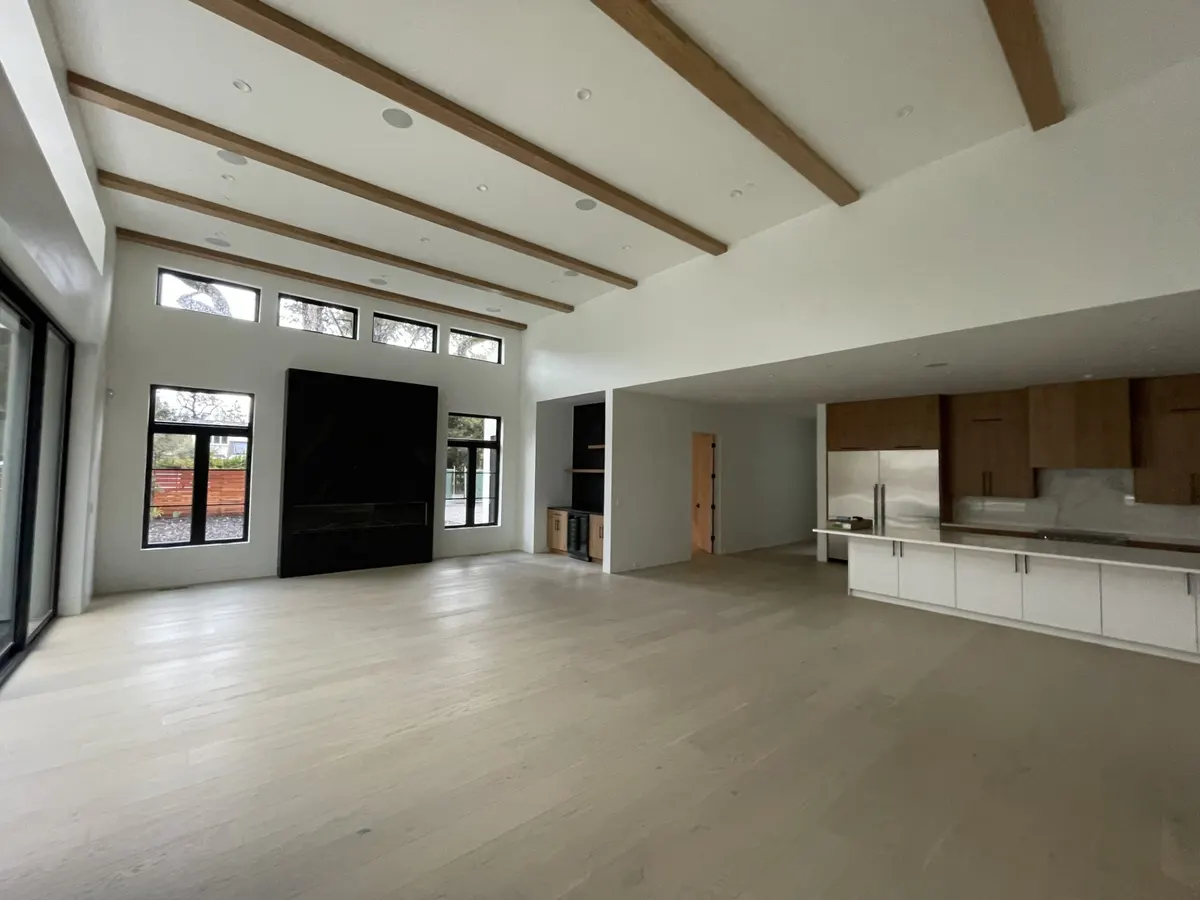 Great room with white walls, exposed wood beams, and a black fireplace wall