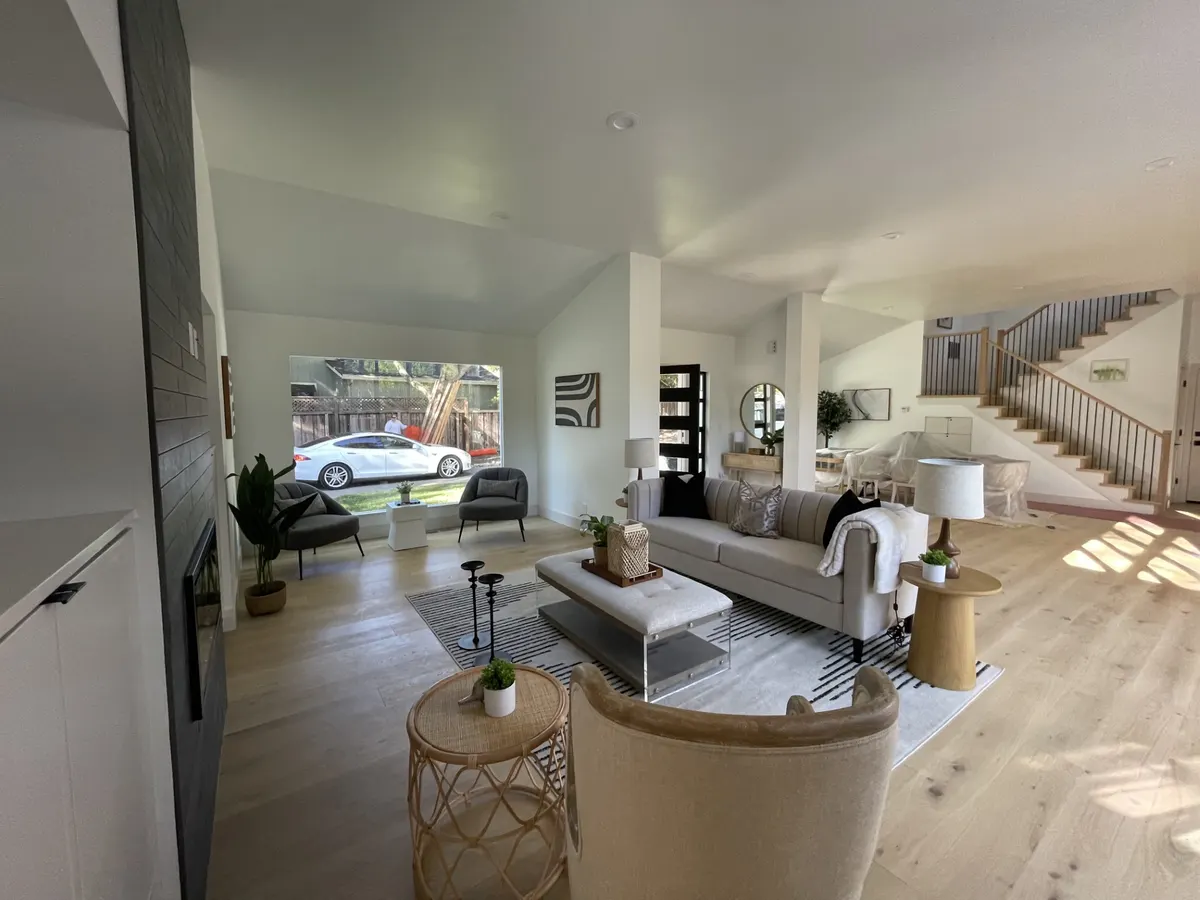 Living room with light oak floors, white walls, and a staircase