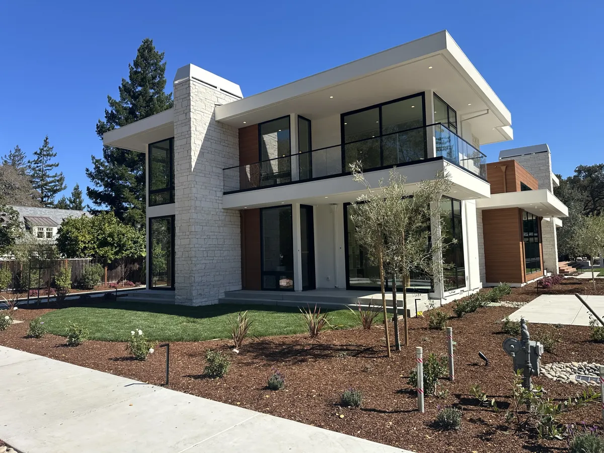 Modern two-story home with stone cladding, wood accents, and glass balconies