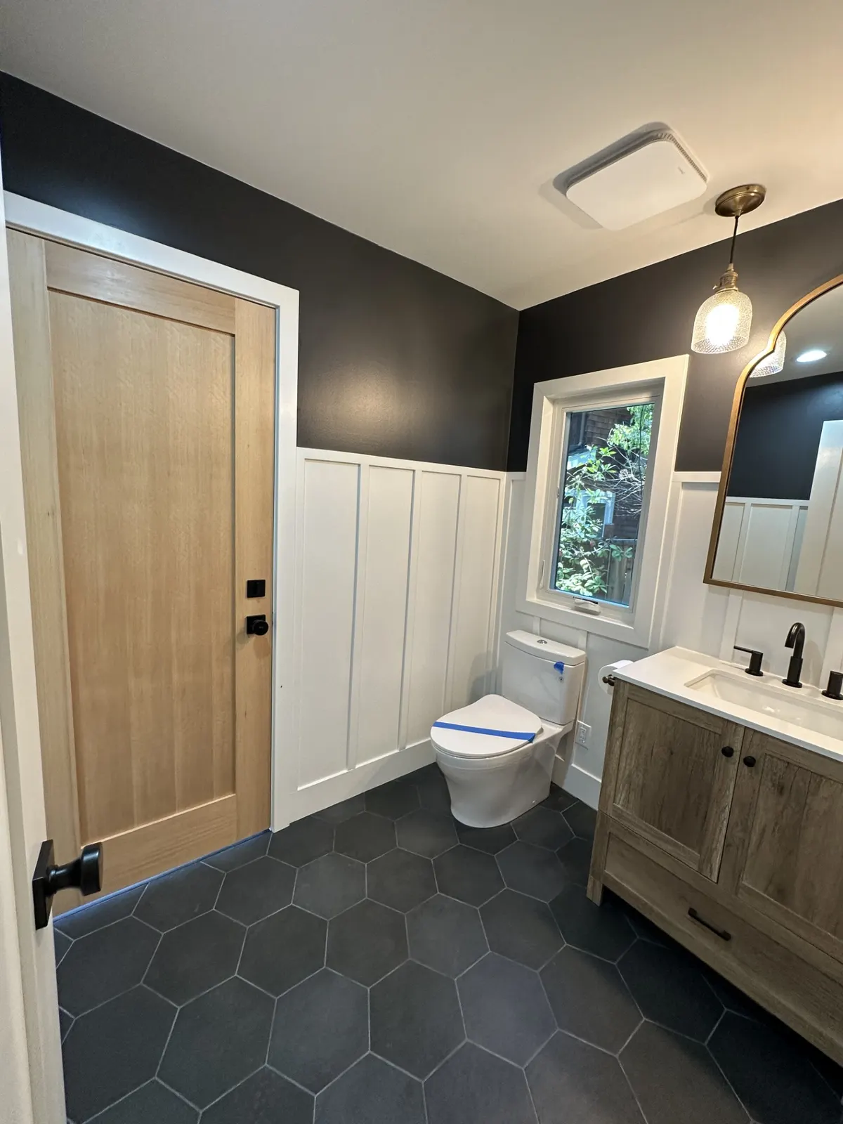 Powder room with dark walls, white wainscoting, and a stained wood door