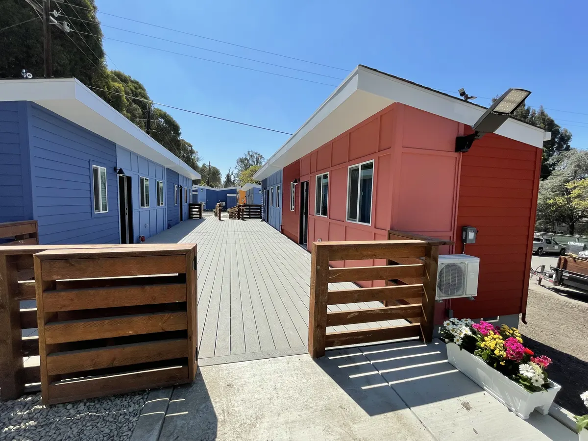 Row of small homes painted blue, red, and yellow with wood ramps and railings