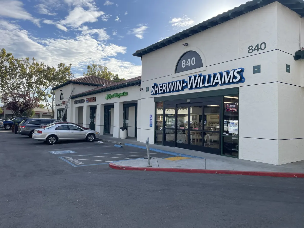 Retail center repainted white with dark trim and storefront signs