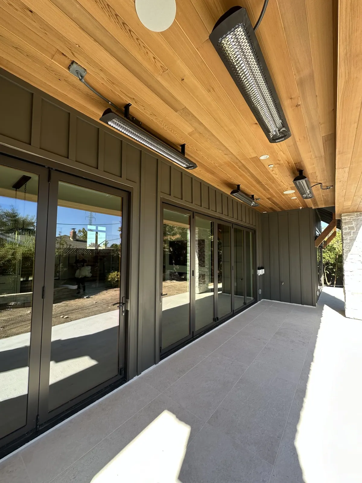 Covered porch with a stained wood ceiling and black-framed glass doors