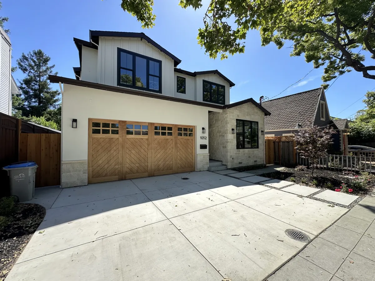 White two-story home with stained wood carriage-style garage doors