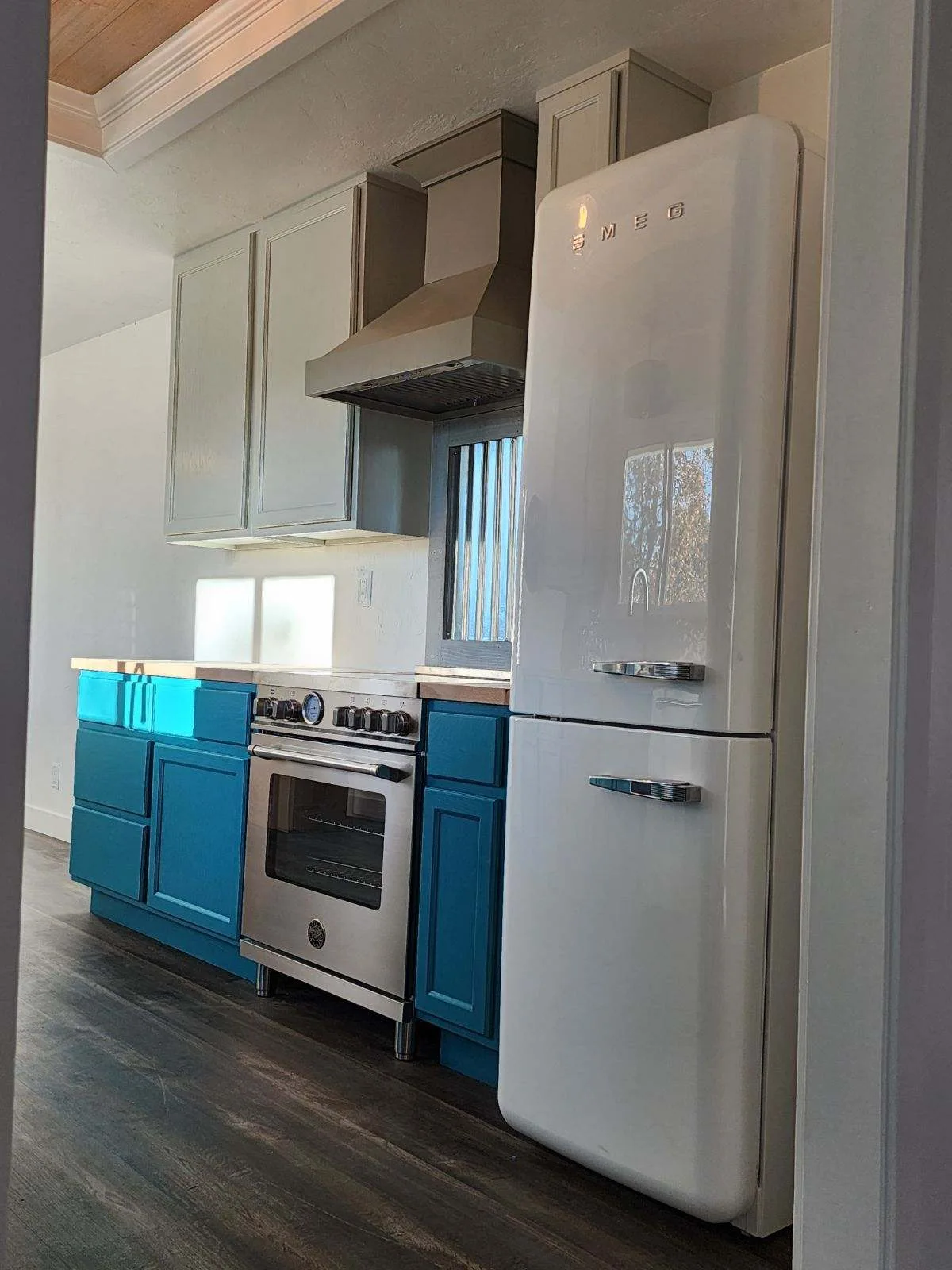 Kitchen with teal lower cabinets, white upper cabinets, and a cream retro refrigerator