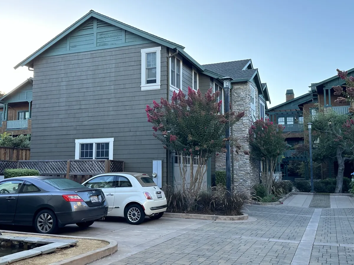 Craftsman townhomes with green shingle siding, stone columns, and stained garage doors