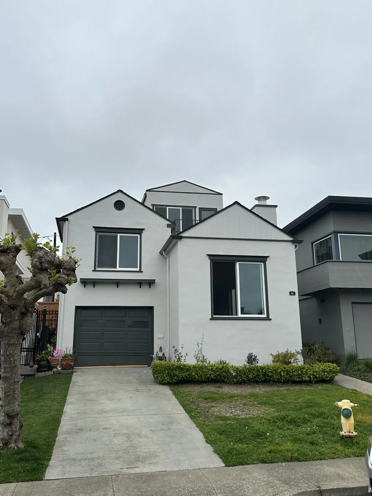 Two-story home painted white with a gray garage door and a green lawn